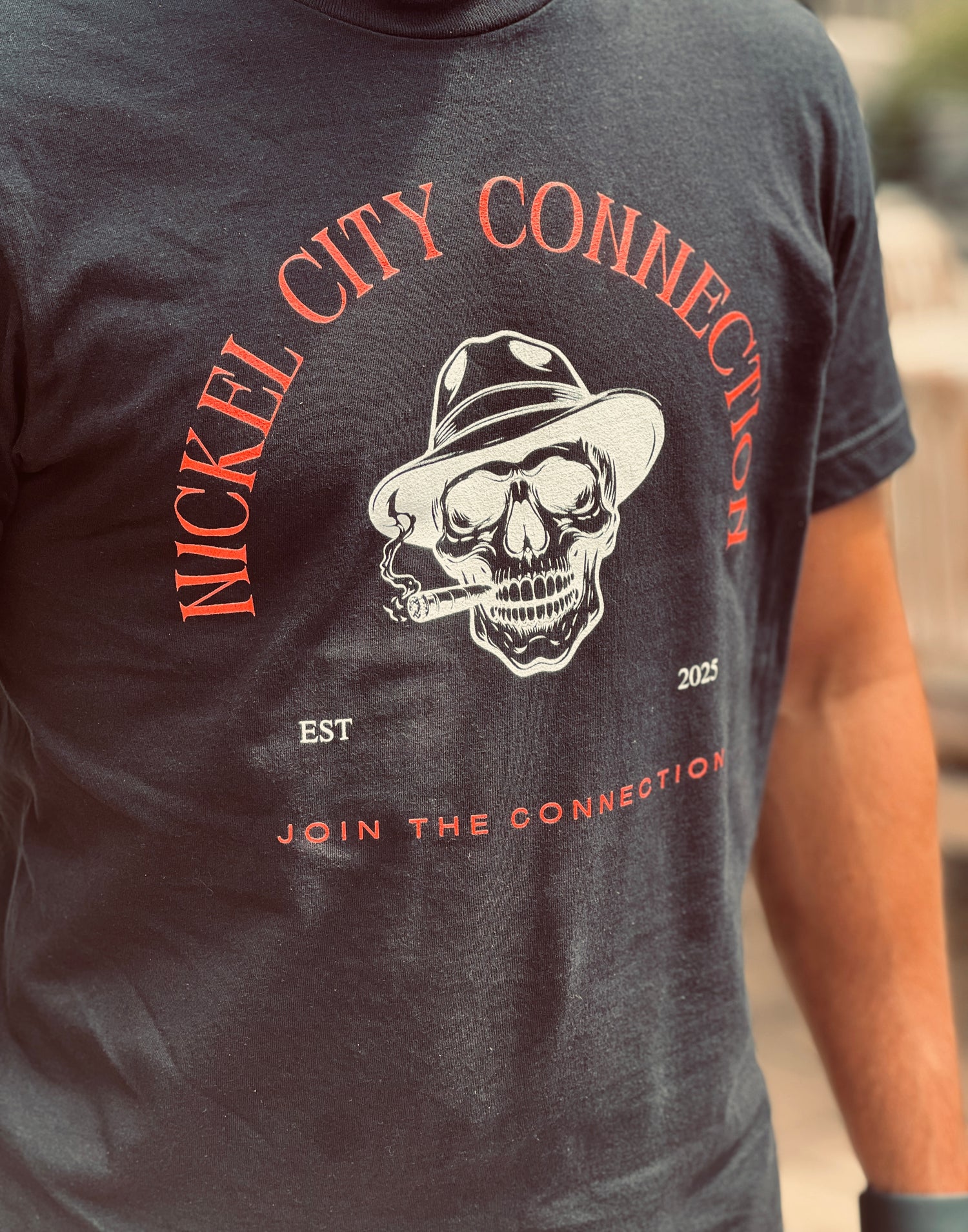 Nickel City Connection shirt with skull on it smoking cigar and wearing fedora