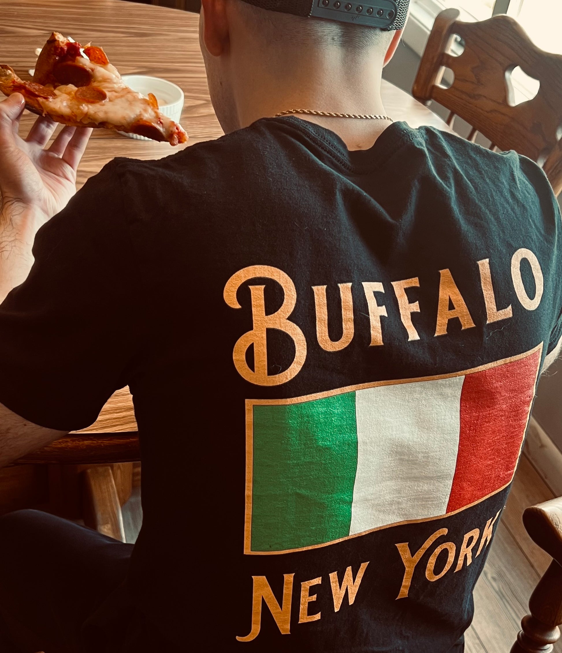 Man wearing buffalo ny shirt with Italy flag and eating pizza 