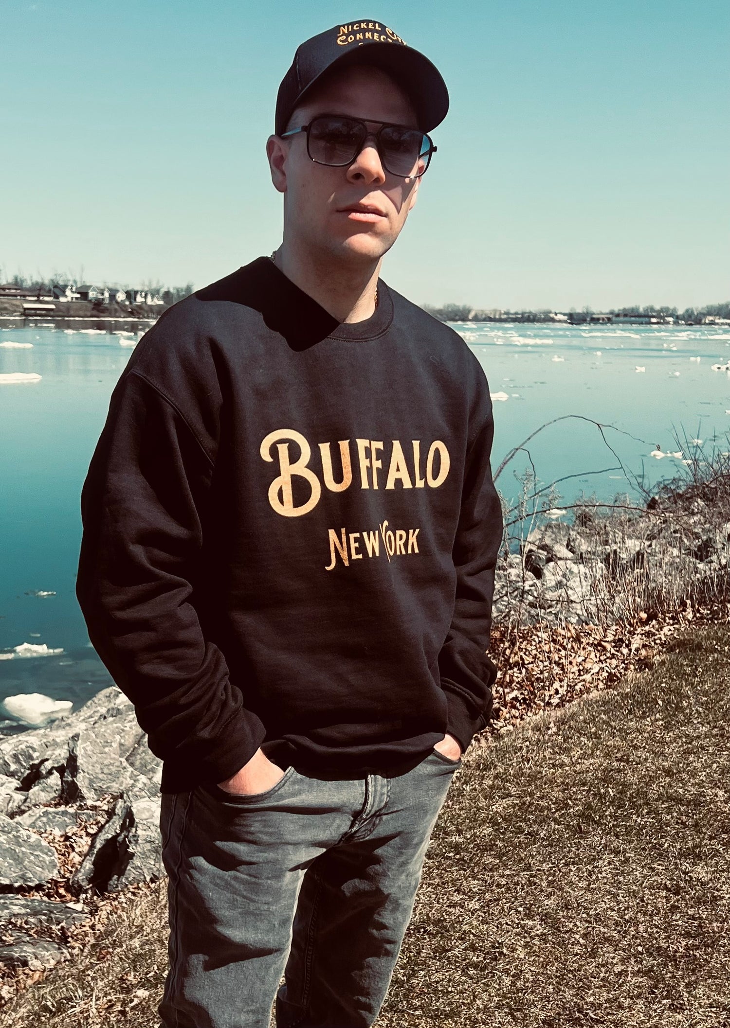 Man wearing black Buffalo sweatshirt by water