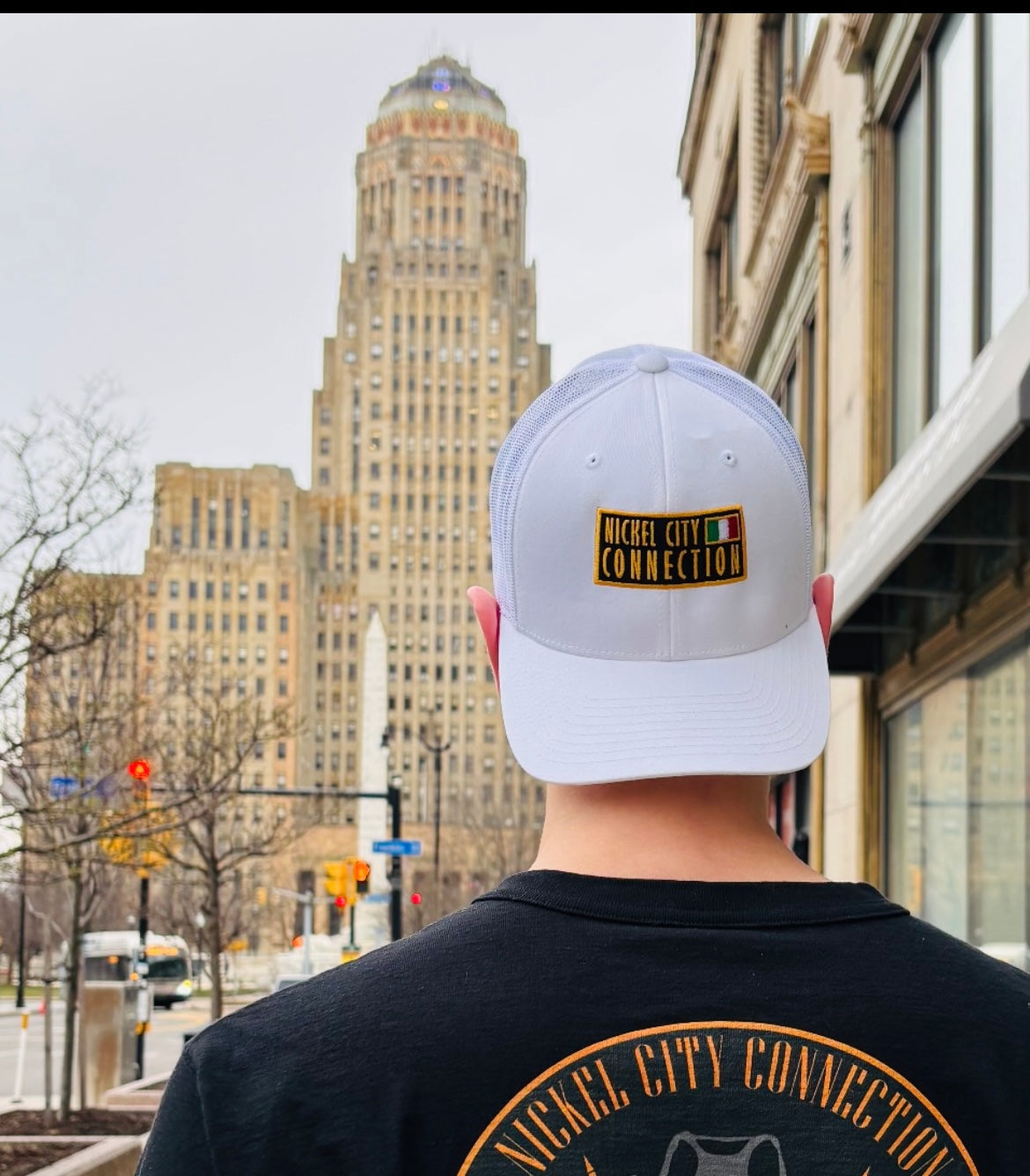 Man wearing nickel city connection hat in front of Buffalo city hall