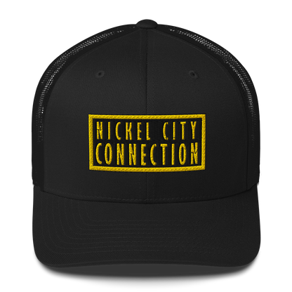 A Black trucker-style cap with a black and yellow embroidered patch on the front. The patch has bold yellow text reading 'NICKEL CITY CONNECTION' inside a black background with a yellow border.