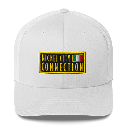 White trucker hat featuring an embroidered patch design featuring the text "NICKEL CITY CONNECTION" in bold, yellow capital letters on a black background. The text is enclosed in a yellow rectangular border. To the right of the text, there is a small embroidered Italian flag with green, white, and red vertical stripes, also bordered in yellow.